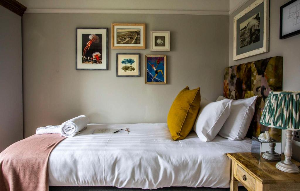 a bedroom with a large white bed with pictures on the wall at Dunstan House in Burnham on Sea