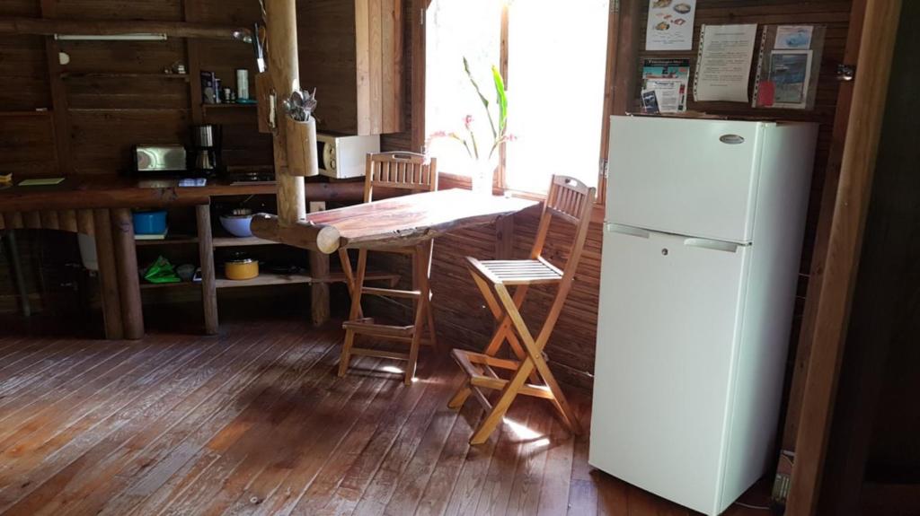 a kitchen with a refrigerator and a table and chairs at Domaine de Robinson in Les Anses-dʼArlets