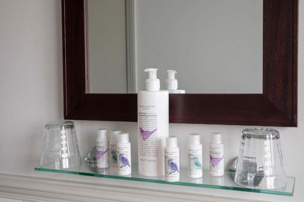 a shelf with a bunch of shampoo bottles and a mirror at Dunstan House in Burnham on Sea