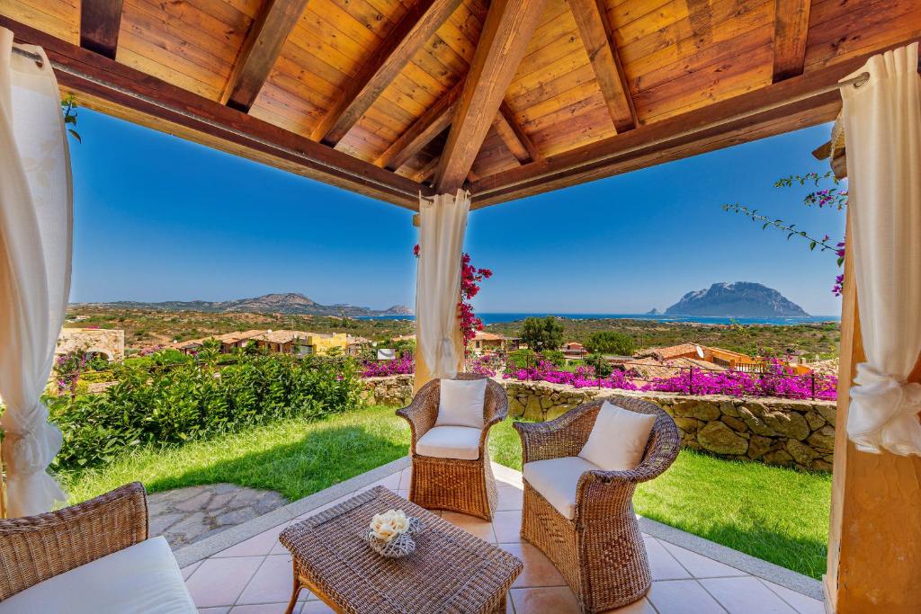 patio con sillas y mesa y vistas a la montaña en Villa con vista Porto San Paolo, en Porto San Paolo