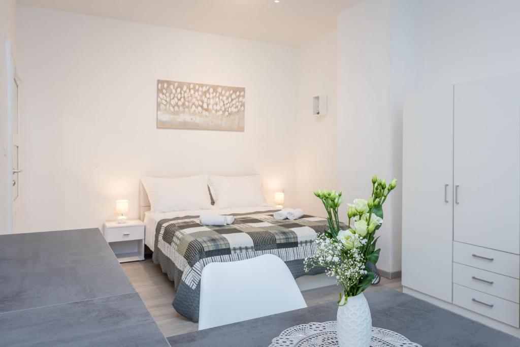 a white bedroom with a bed and a vase of flowers at Apartment Matea in Split
