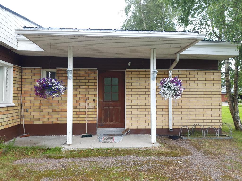 une maison avec une terrasse couverte et 2 paniers de fleurs dans l'établissement Pulmustie 19as2 Huoneisto, à Ylivieska