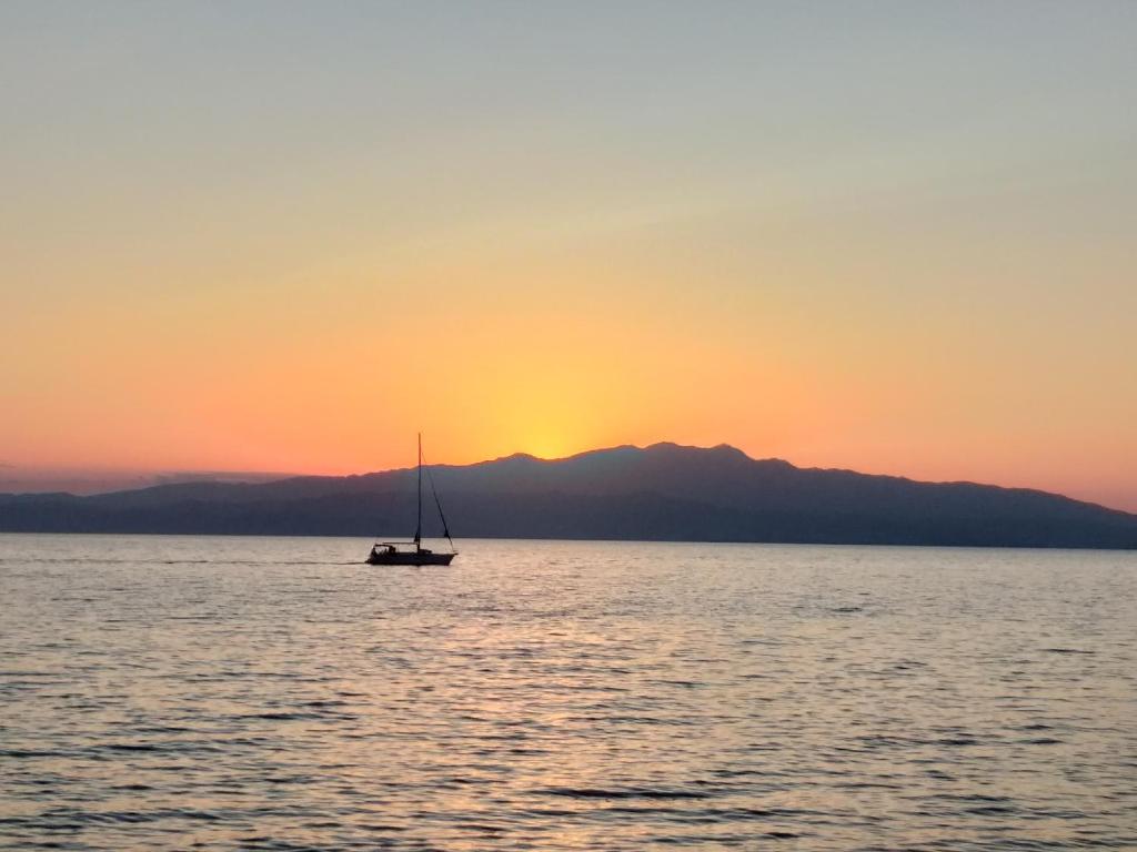 a sail boat in the ocean at sunset at Sea View Bungalows in Skala Kallirachis