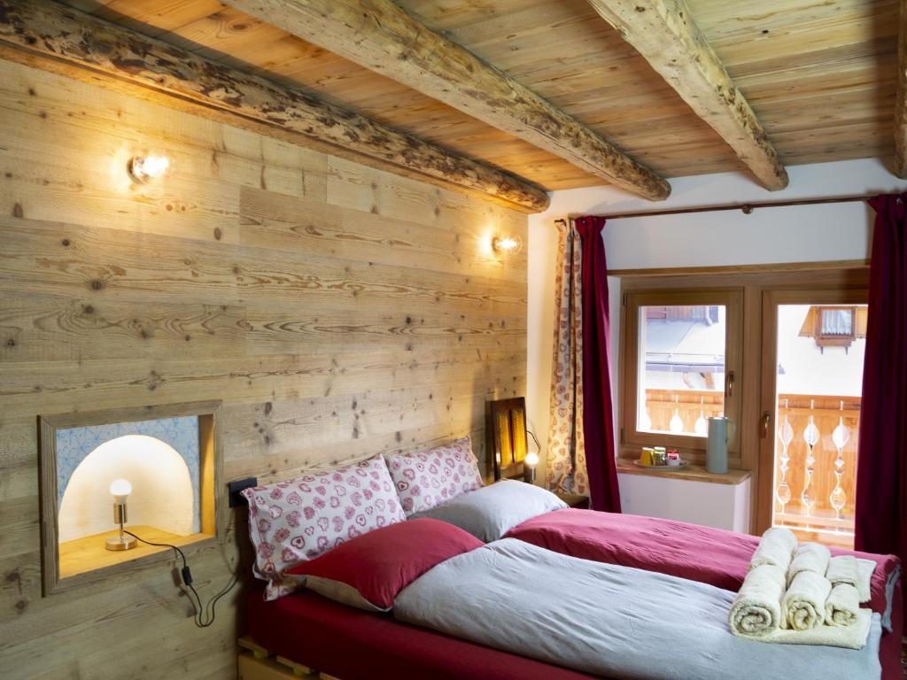 ein Schlafzimmer mit einer Holzwand und einem Bett in der Unterkunft B&B Cedavécia in Comèlico Superiore