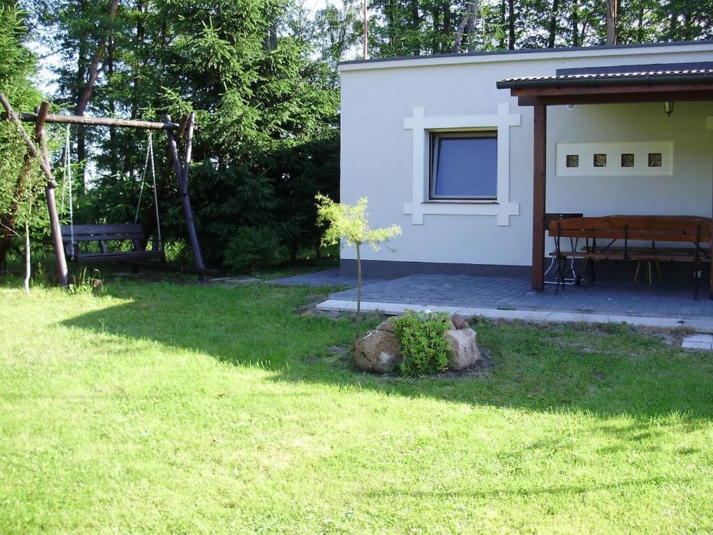 een kleine boom in een tuin naast een huis bij Dom wakacyjny bezpośrednio przy Jeziorze Białym in Okuninka