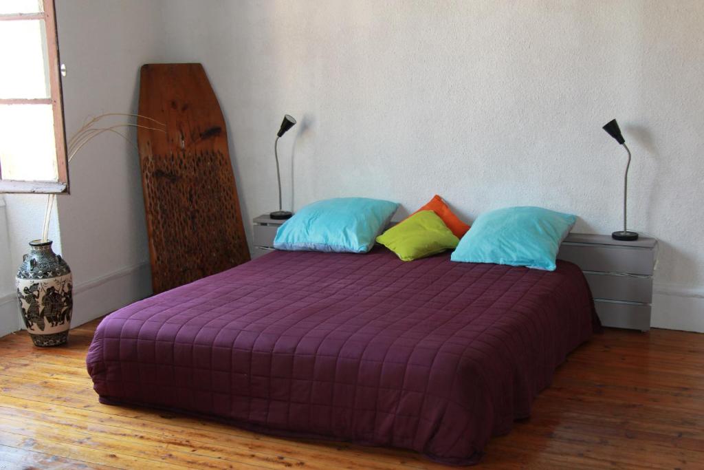 una camera con letto viola e 2 cuscini di Chambre cozy et Salon de 60 m2 au coeur de la cité a Cordes-sur-Ciel