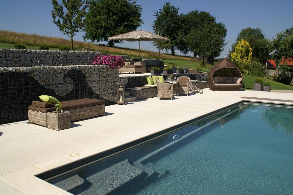 a swimming pool in a yard with a stone wall at Der Heindlhof in Neualbenreuth