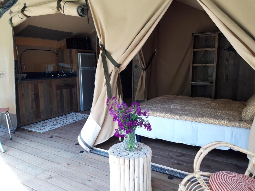a bedroom with a bed and flowers in a tent at Camping La Bohème in Tournon-sur-Rhône