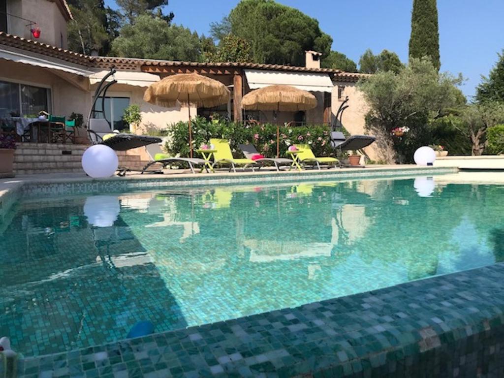 ein großer Pool mit Stühlen und Sonnenschirmen in der Unterkunft villa santa rita in Auribeau-sur-Siagne