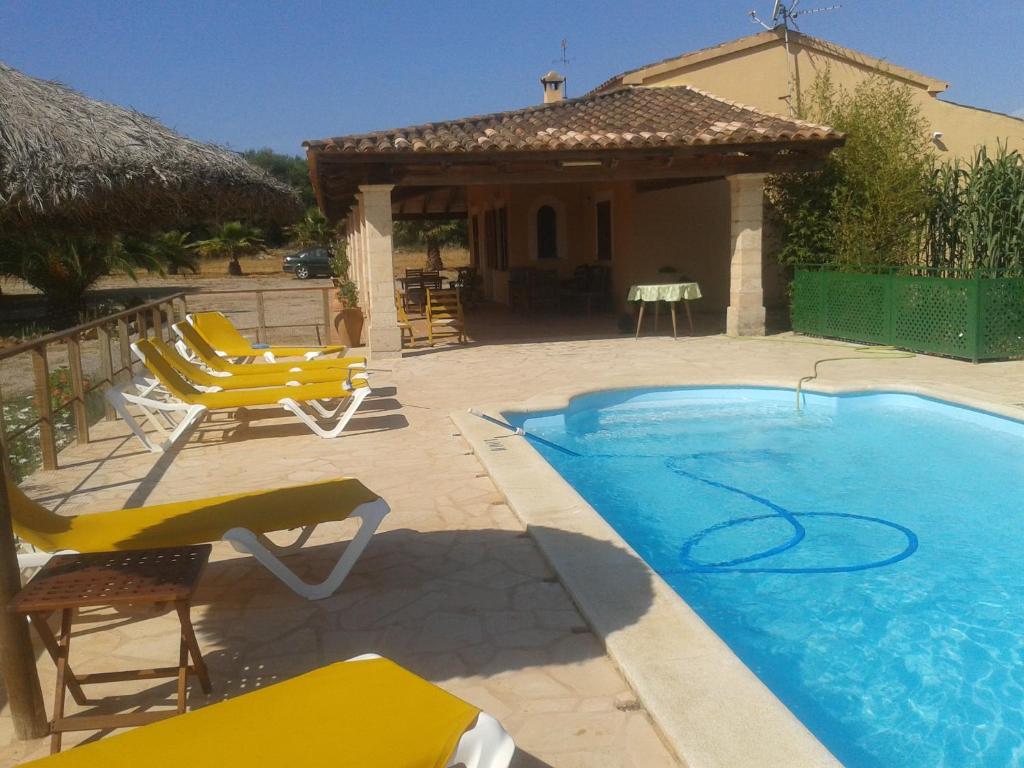 una piscina con sillas amarillas y una casa en Casa Rural cerca Es Trenc en Campos