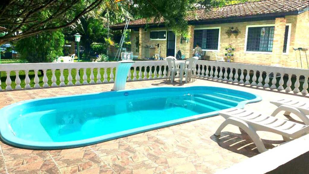 una piscina con due sedie accanto a una recinzione di Casa Mar & Rio Ubatuba a Ubatuba