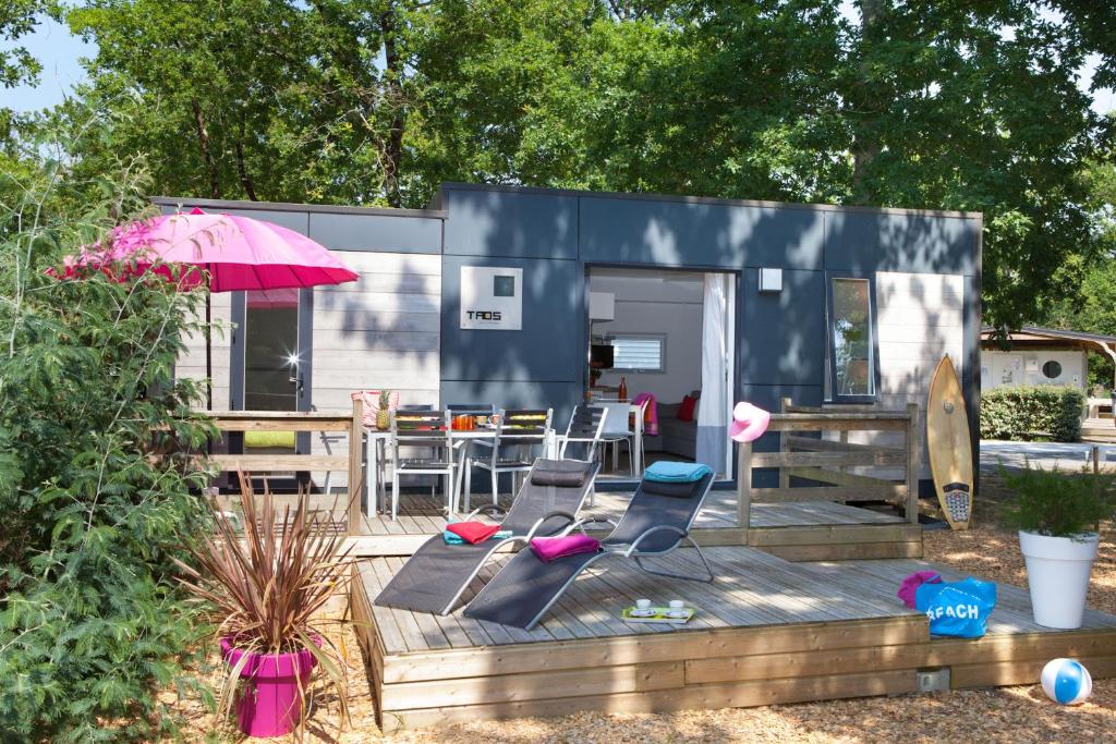 a blue tiny house with chairs and an umbrella at Mobil home Domaine de Soulac in Soulac-sur-Mer