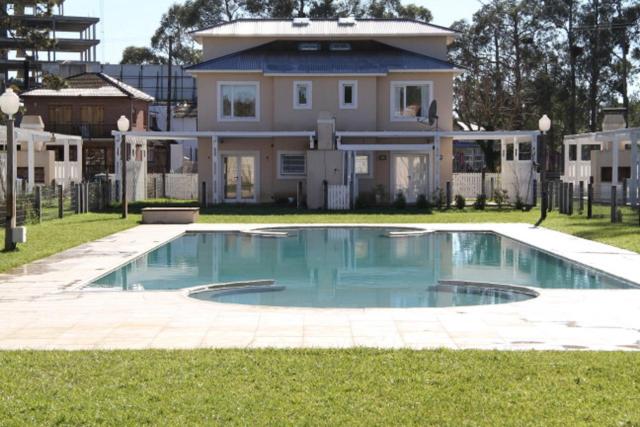 une maison avec une piscine en face d'une maison dans l'établissement Complejo Tridente, à Pinamar