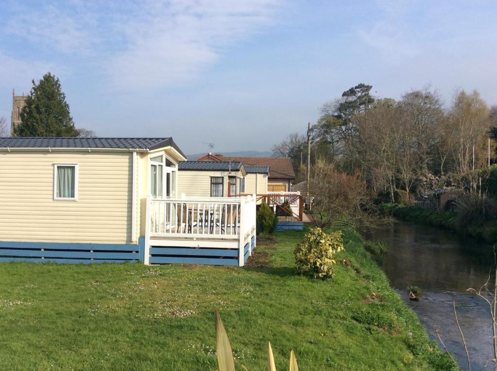 a house with a deck next to a river at Pet friendly riverside static caravan in Cheddar