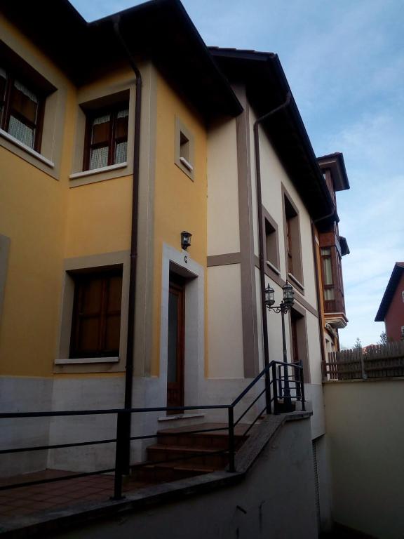 a yellow and white house with stairs in front at Apartamentos La Blanca in Nueva de Llanes