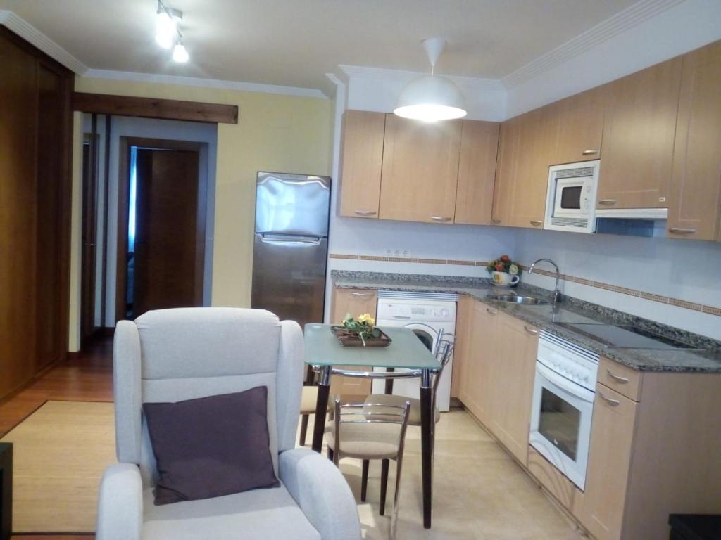 a kitchen with a table and chairs in a room at Apartamentos La Blanca in Nueva de Llanes
