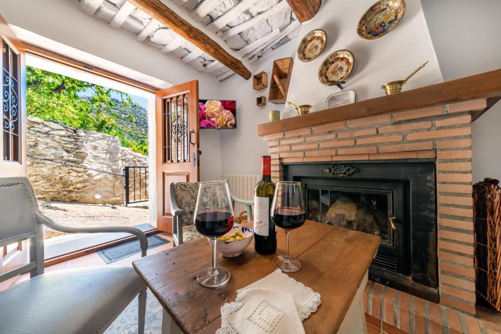 a living room with a fireplace and two glasses of wine at Casa Tita María in Bubión