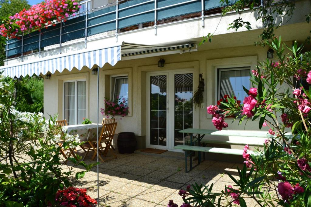 une terrasse couverte d'une maison avec un banc et des fleurs dans l'établissement Anna Apartment, à Budaörs