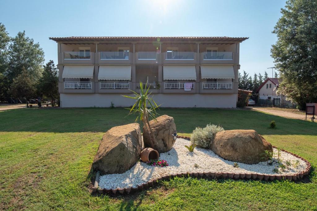a building with two large rocks in a yard at Camping Linaraki Apartments & Bungalows in Sykia Chalkidikis