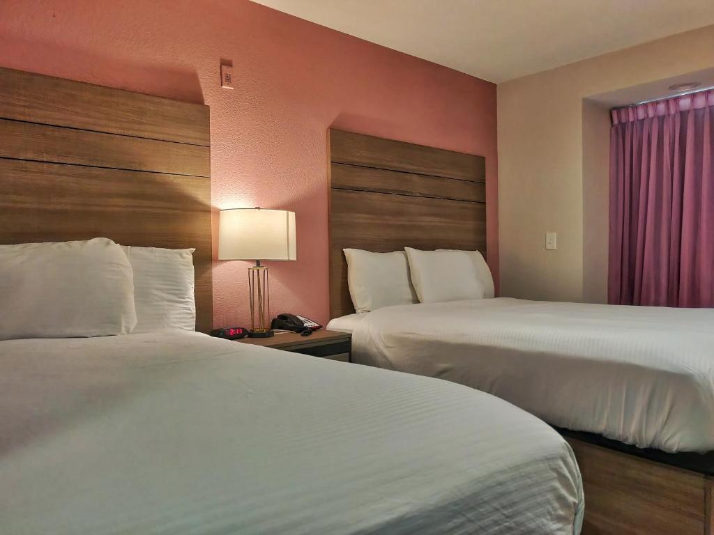 a hotel room with two beds and a window at Arya Inn and Suites in Irving