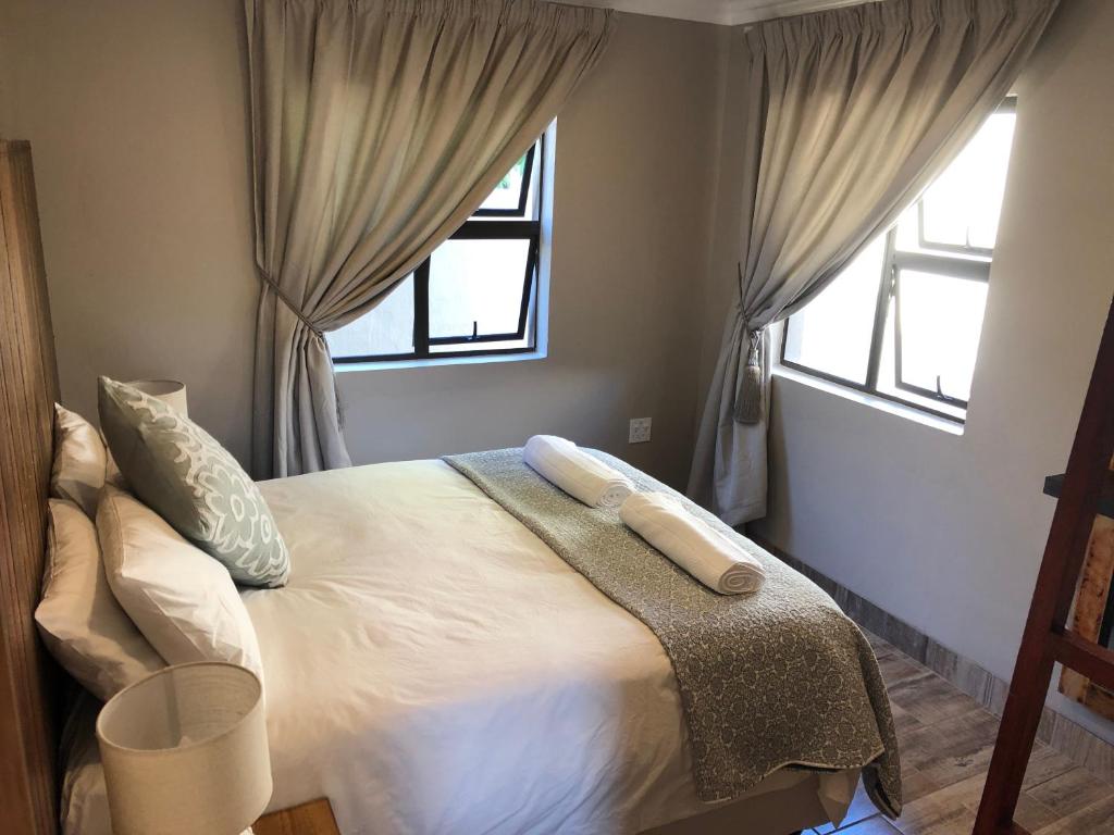 1 dormitorio con 1 cama grande y 2 ventanas en Ginger Barn, en Pretoria