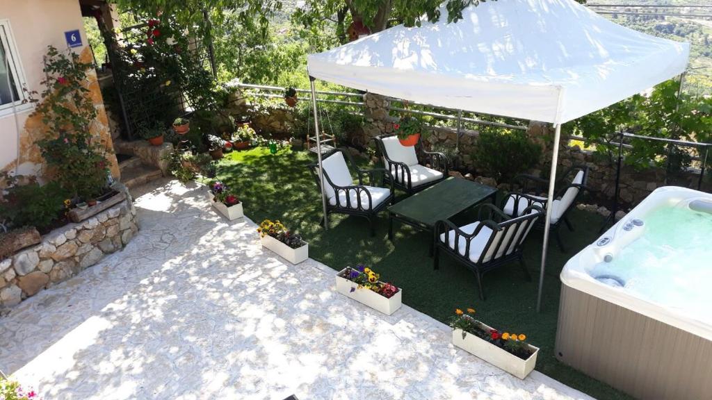 un patio con tavolo, sedie e vasca idromassaggio di RELAX HOUSE a Solin (Salona)