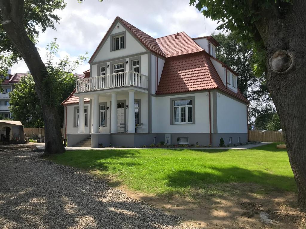 duży biały dom z czerwonym dachem w obiekcie Dworek Nadmorski we Władysławowie