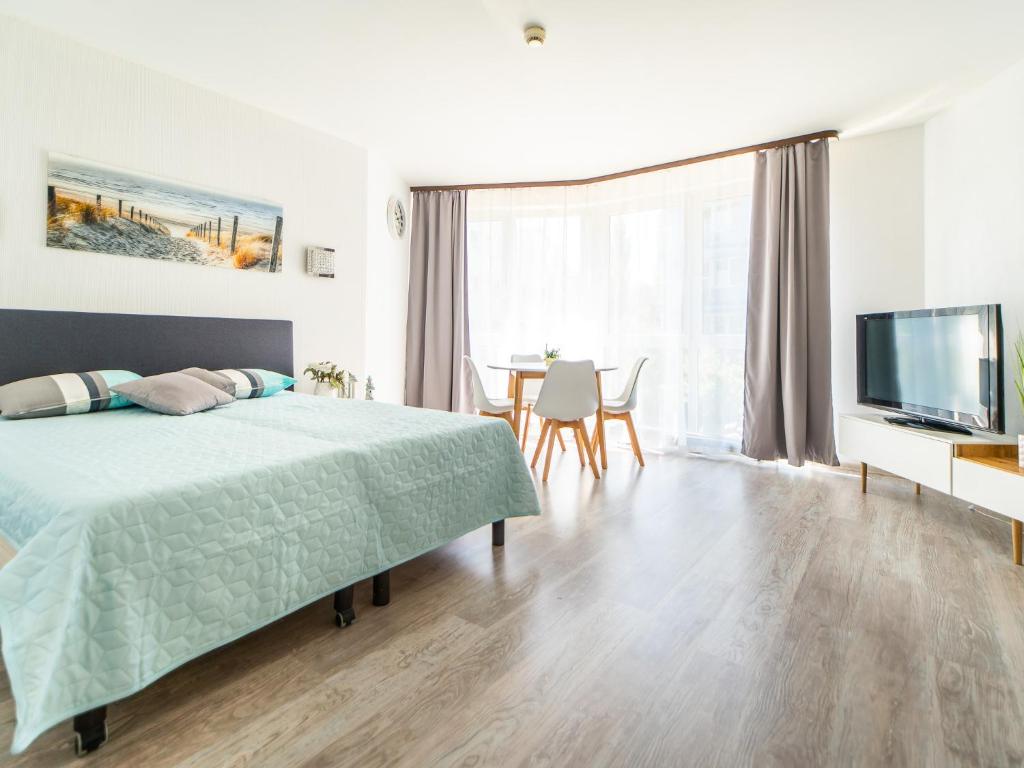 a bedroom with a bed and a table and a television at Apartament Awangardia 250m od morza in Kołobrzeg