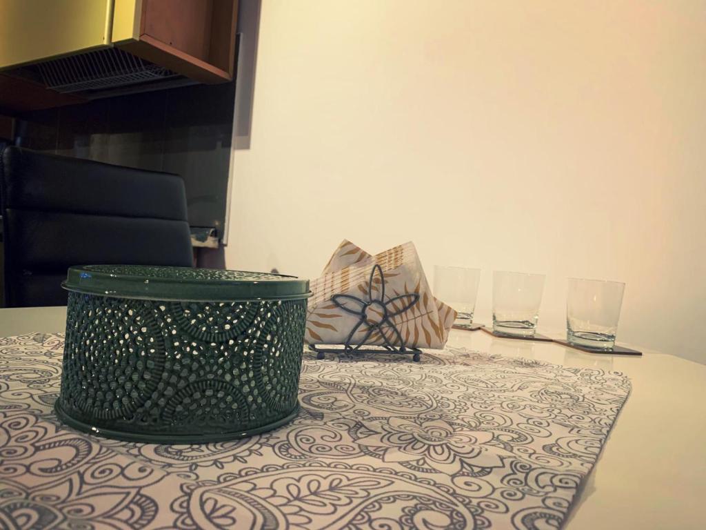 a green trash can sitting on a table with two glasses at Lux Apartament in Zalău