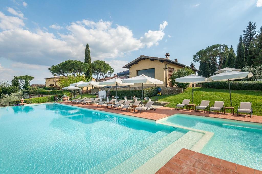 a swimming pool with chairs and umbrellas at Borgo Divino in Montespertoli