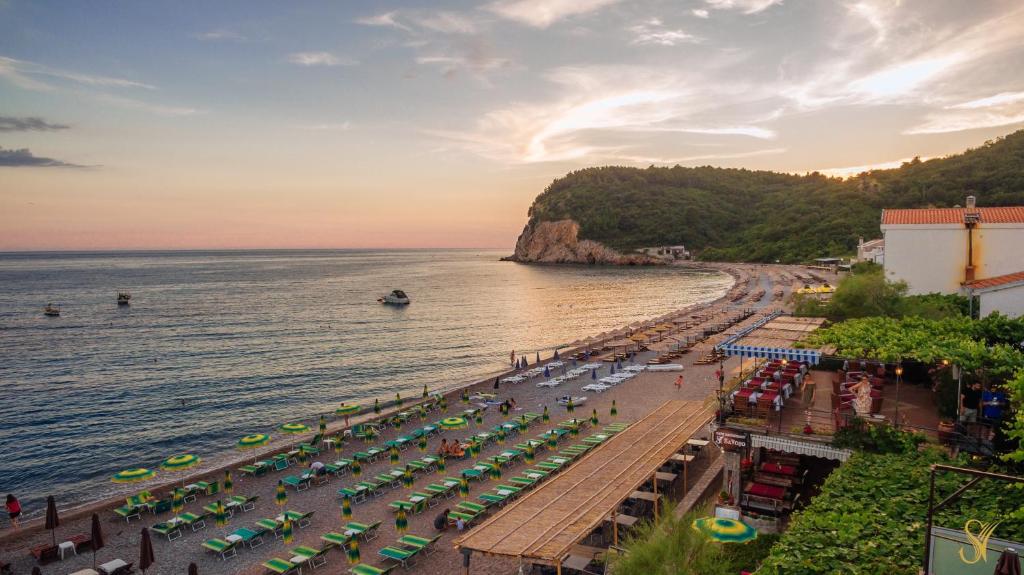 een strand met stoelen en parasols en de oceaan bij Hotel Savojo in Petrovac na Moru