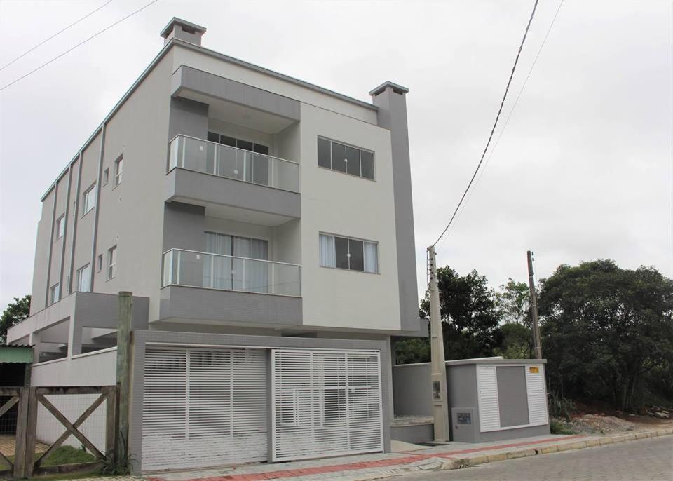 a large white building with a garage at Ametista Residence in Bombinhas
