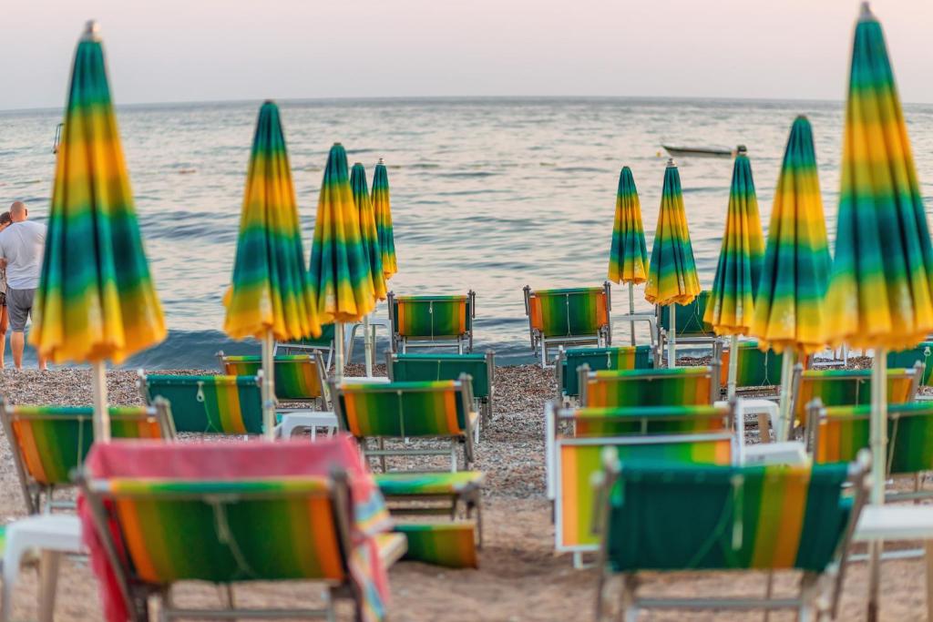 a group of beach chairs and umbrellas on the beach at Hotel Savojo in Petrovac na Moru