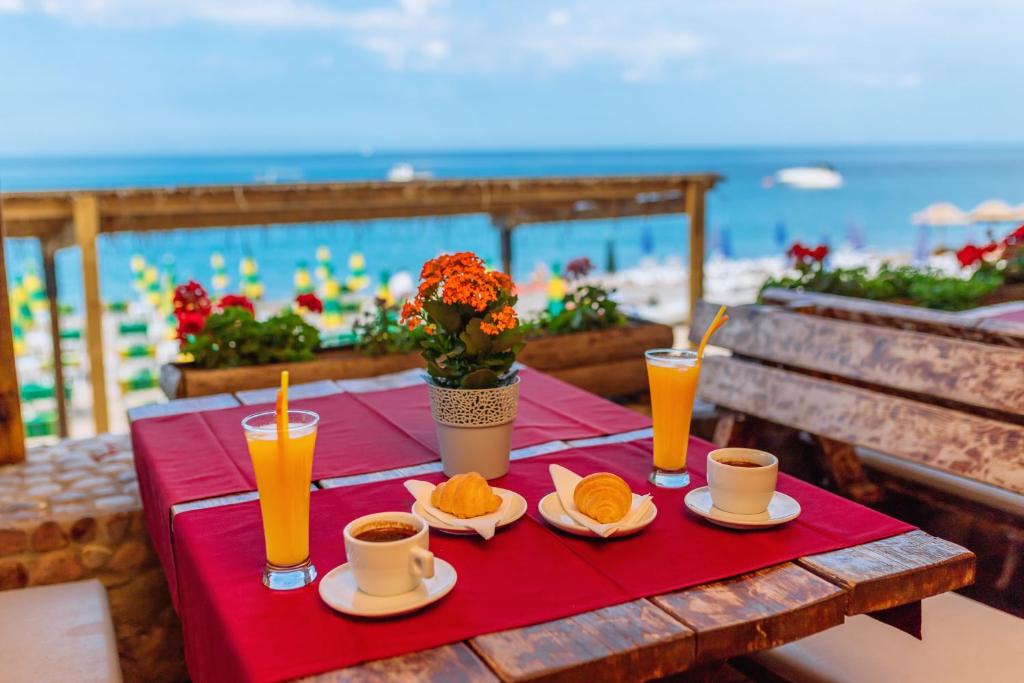 a table with cups and plates of oranges and drinks on the beach at Hotel Savojo in Petrovac na Moru