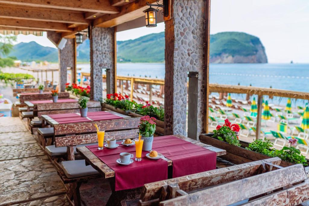 a row of tables on a patio with a beach at Hotel Savojo in Petrovac na Moru