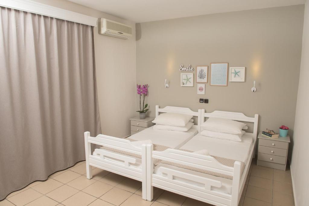 a white bedroom with two white beds in it at Aqua Beachfront Elegant Hotel in Olympic Beach