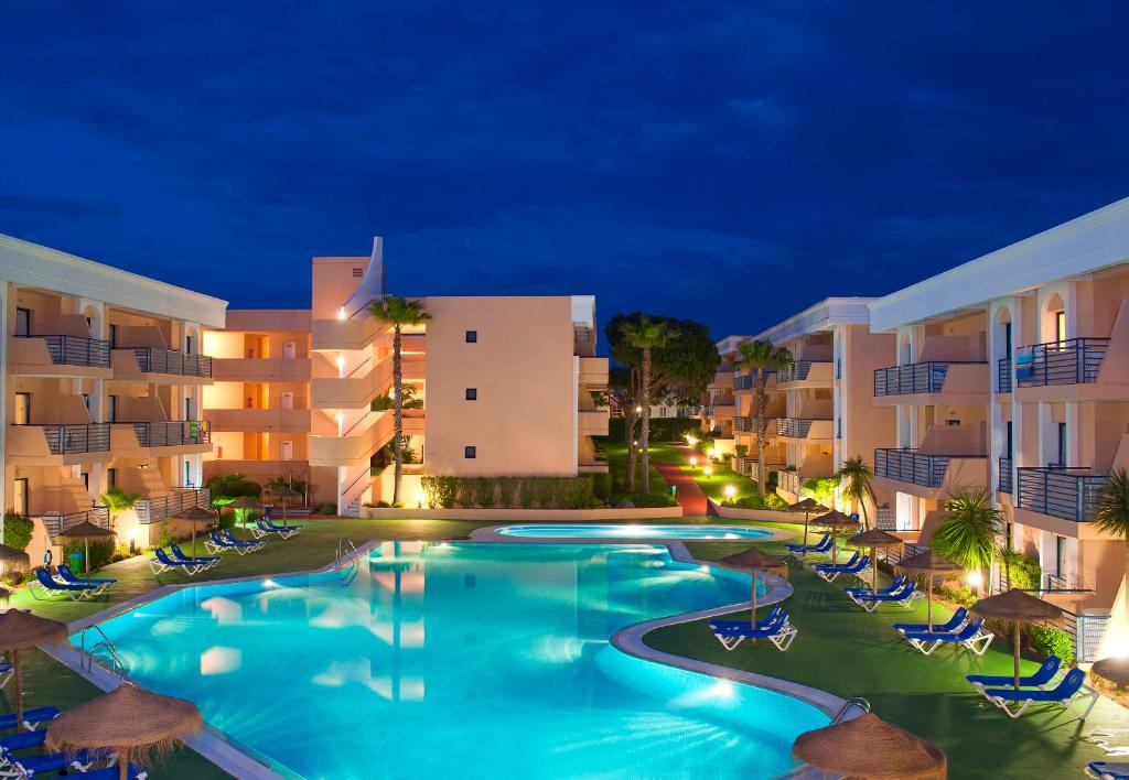 a swimming pool in front of a hotel at night at Sol Sancti Petri Aparthotel in Chiclana de la Frontera