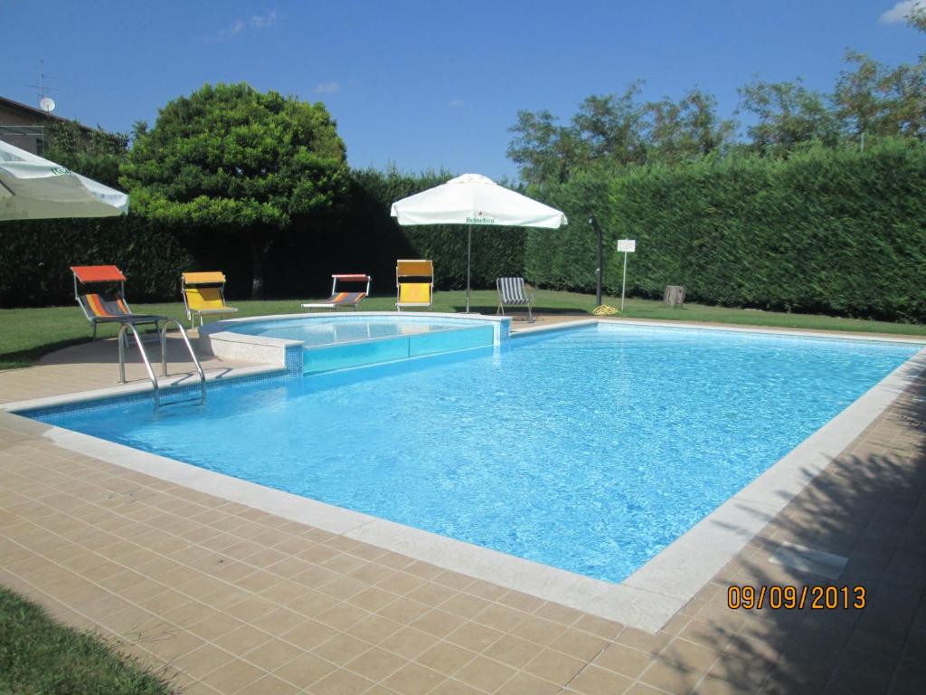 a swimming pool with chairs and an umbrella at Hotel Doria - Business & Bike Hotel in Ostiglia