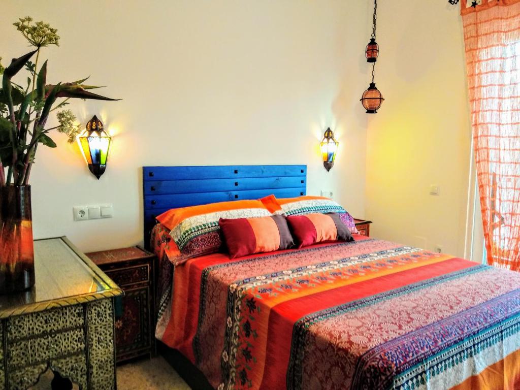 a bedroom with a bed with colorful blankets and pillows at La Barrosa duplex in Chiclana de la Frontera