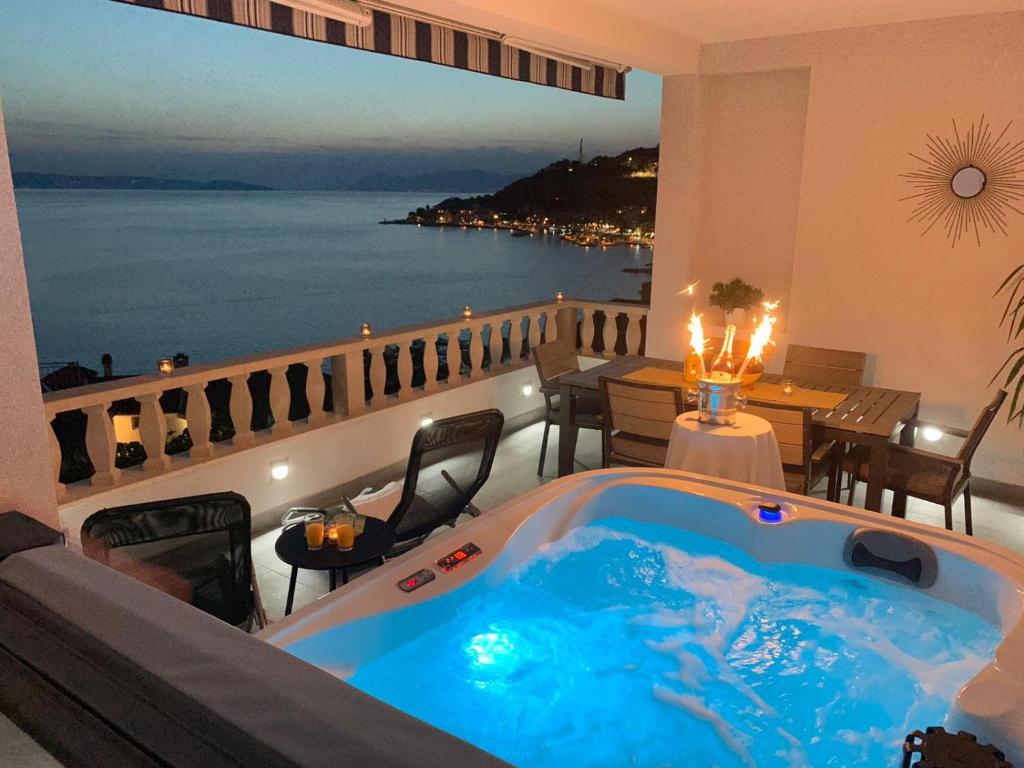 a bath tub on a balcony with a view of the ocean at Apartments Villa Joy in Podgora