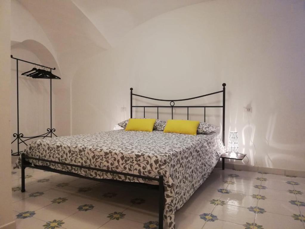 una camera da letto con letto con telaio nero e cuscini gialli di Il Puntino ad Atrani