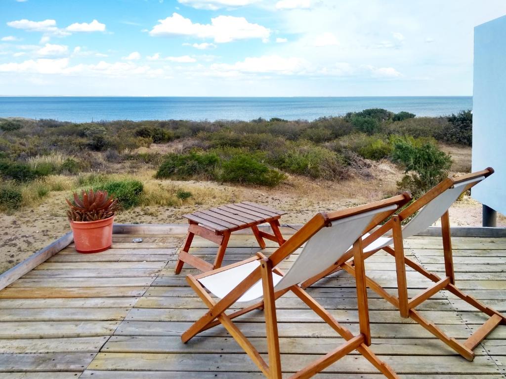 een paar stoelen en een tafel op een houten terras bij Médanos Patagonia in Las Grutas