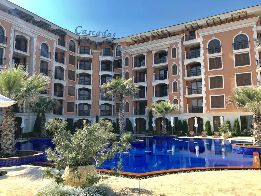 ein Hotel mit einem blauen Pool vor einem Gebäude in der Unterkunft Cascadas Ravda Apartment in Rawda