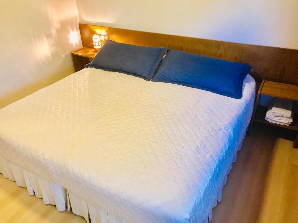 a large white bed with a blue pillow on it at Regency Bombal Apartments in Mendoza