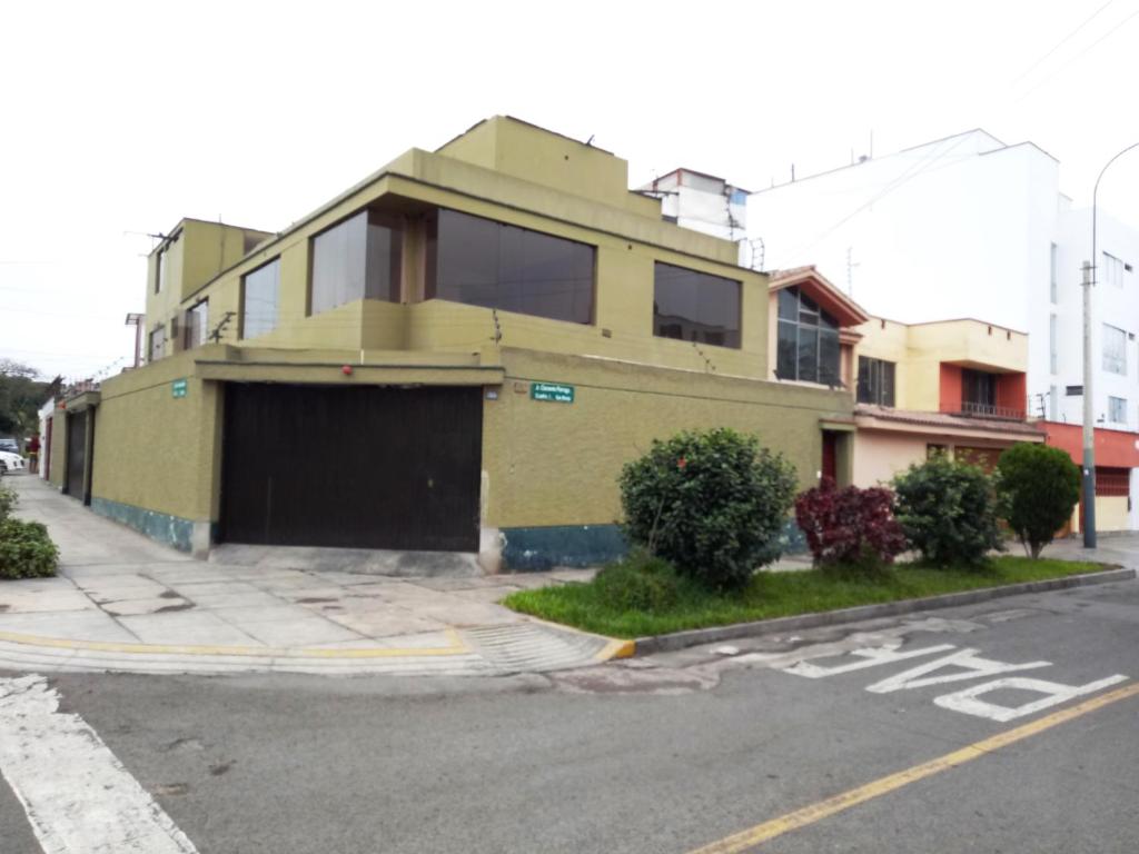 um edifício amarelo com uma garagem ao lado de uma rua em Sucesac em Lima