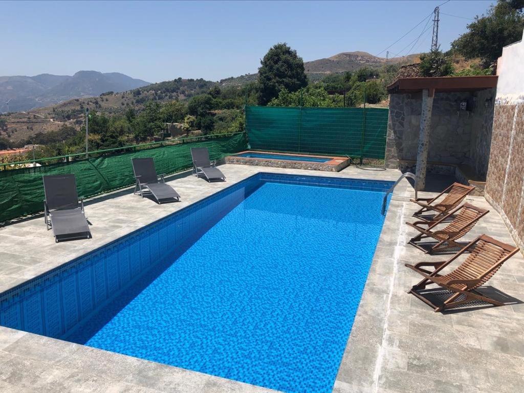 una piscina azul con sillas y una piscina en El Aguacate en Lanjarón