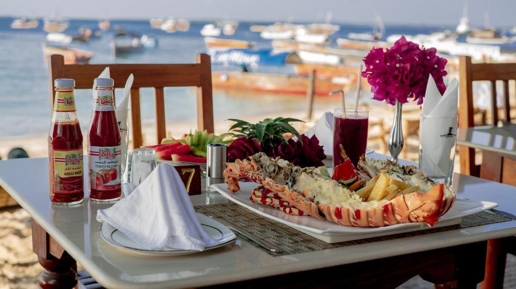 a table with a plate of food and drinks on it at Tembo House Hotel in Zanzibar City
