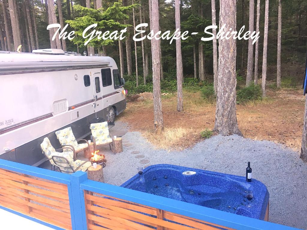 una caravana estacionada en el bosque junto a una bañera de hidromasaje en The Great Escape - Shirley, en Sooke
