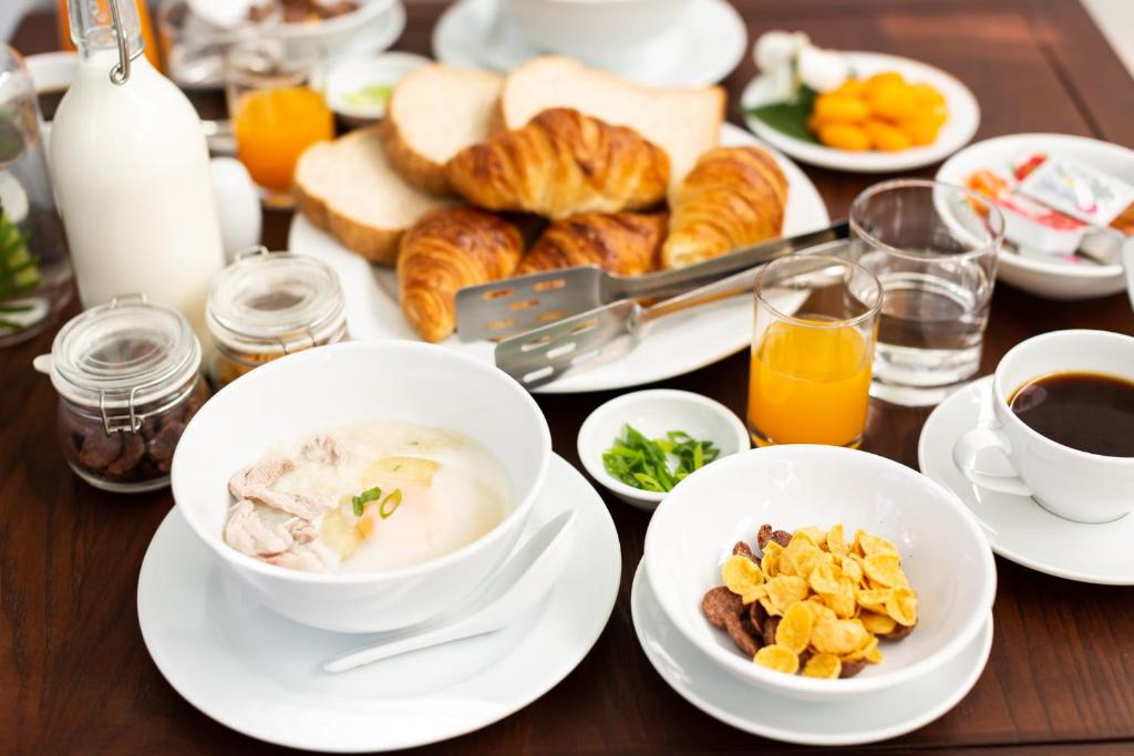 A breakfast table with porridge, cereal, pastries, fruit, juice, and coffee.