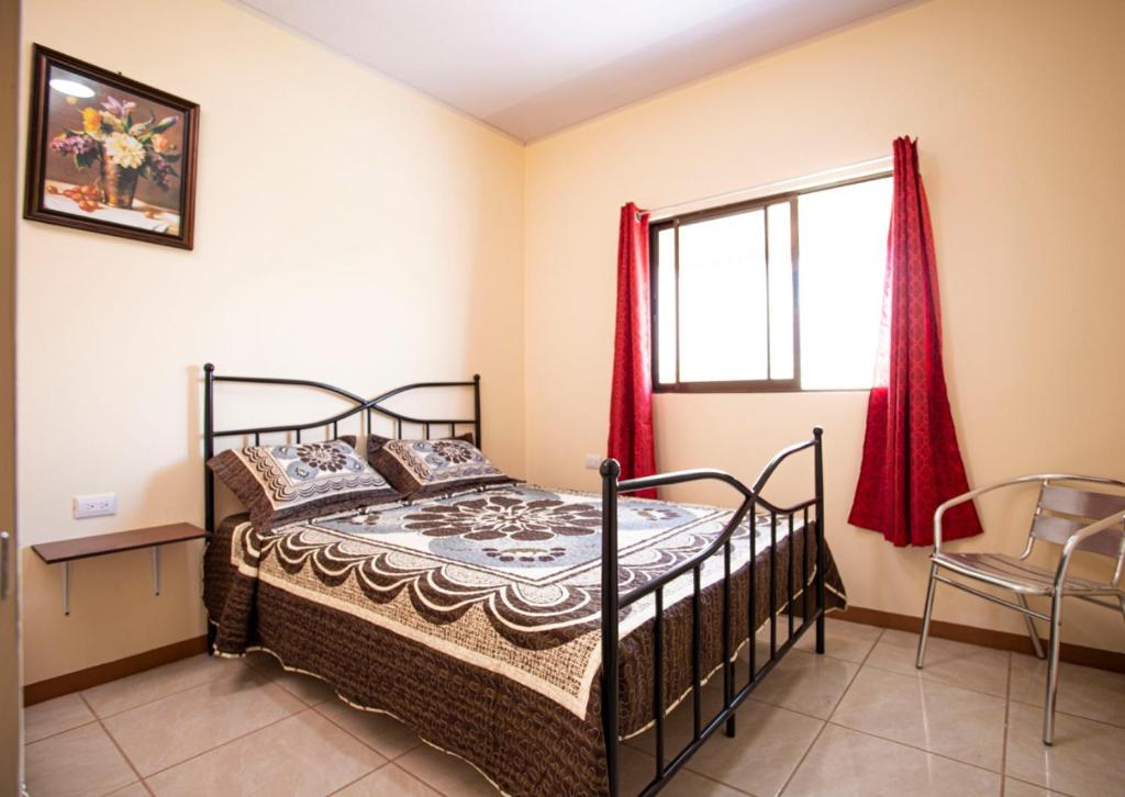 1 dormitorio con 1 cama y una ventana con cortinas rojas en Flor de Katty Hostel Airport en Alajuela